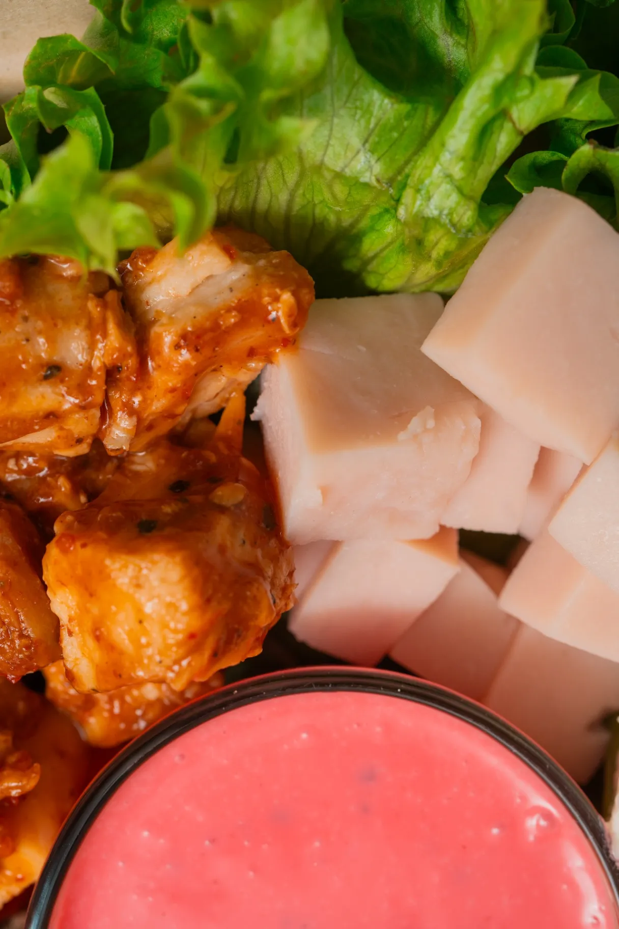 Primer plano de pollo búfalo y jamón sobre lechuga con un vaso de aderezo rosa de la casa