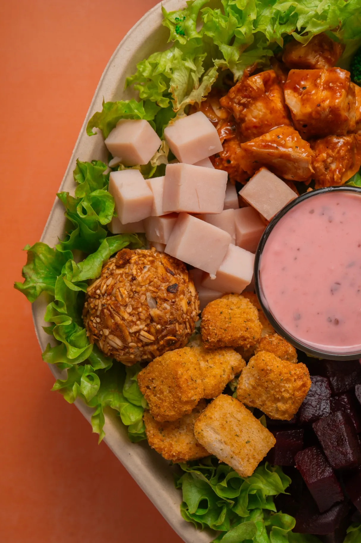Bowl Tasty Greens con jamón, pollo búfalo, nuggets, betabel y aderezo rosa visto desde arriba