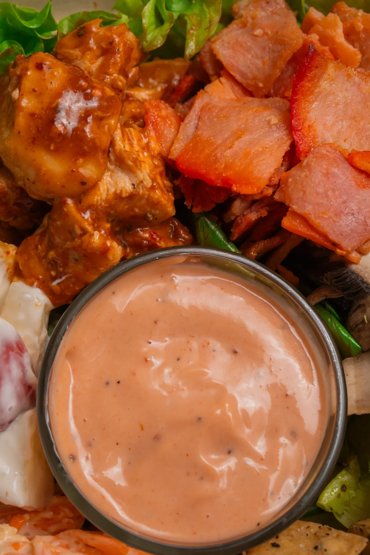 Primer plano de una ensalada Tasty Greens con cubos de salmón, pollo búfalo y aderezo cremoso