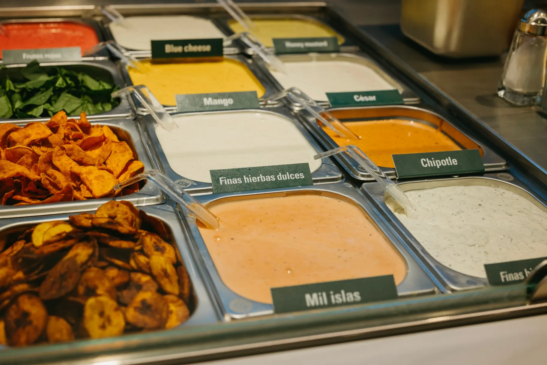 Barra de aderezos Tasty Greens con blue cheese, mango, chipotle, finas hierbas y mil islas etiquetados