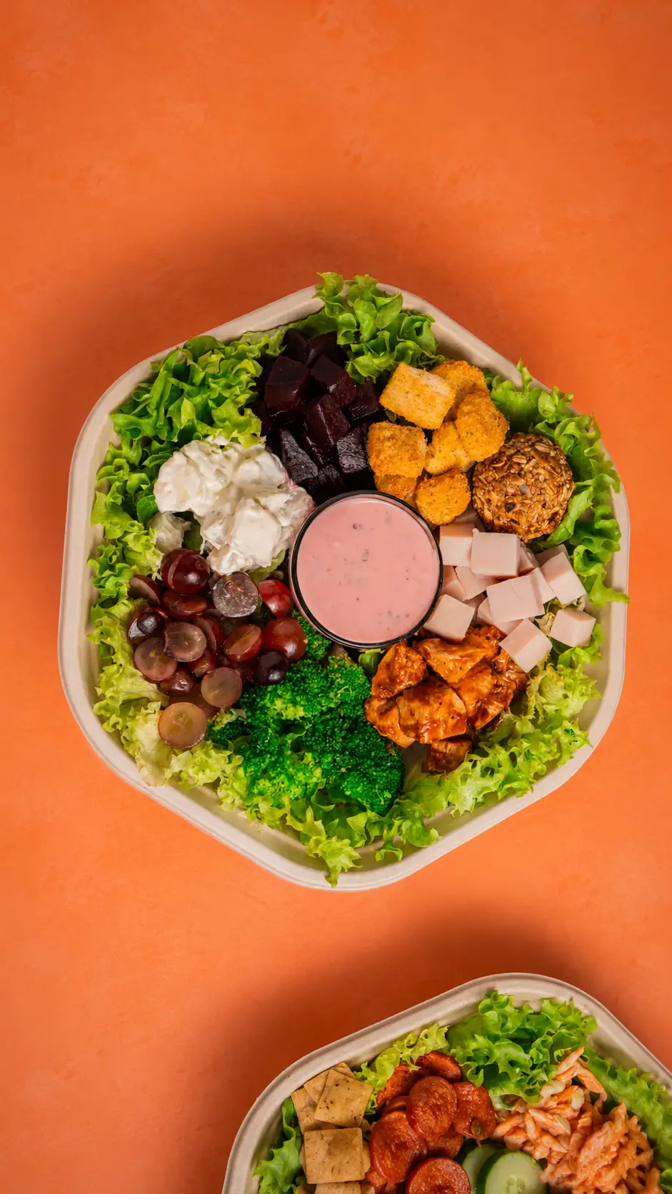 Ensalada Tasty Greens recién armada vista desde arriba, con verdes, fruta y aderezo